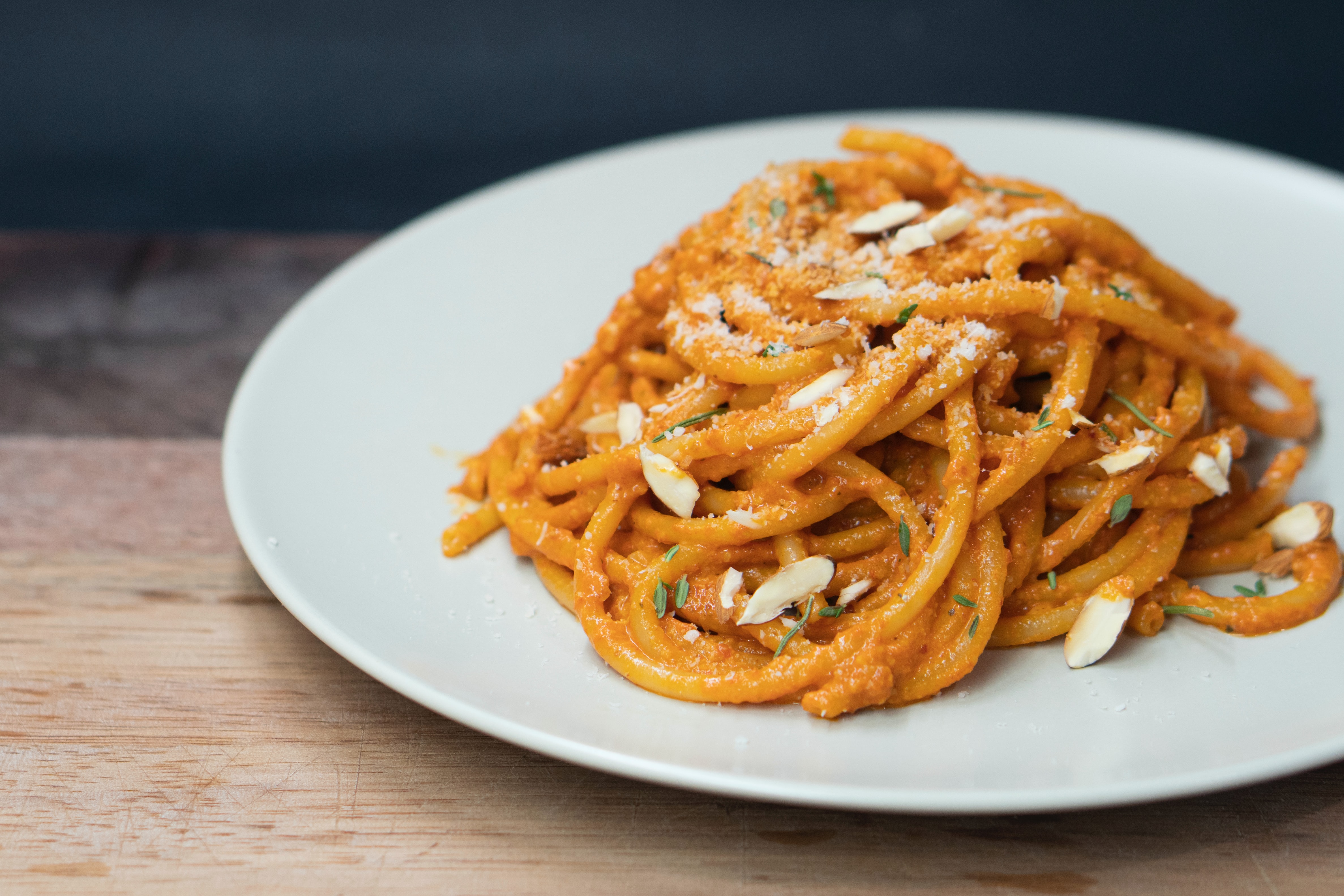 A plate of spaghetti noodles with light red sauce and slivered almonds