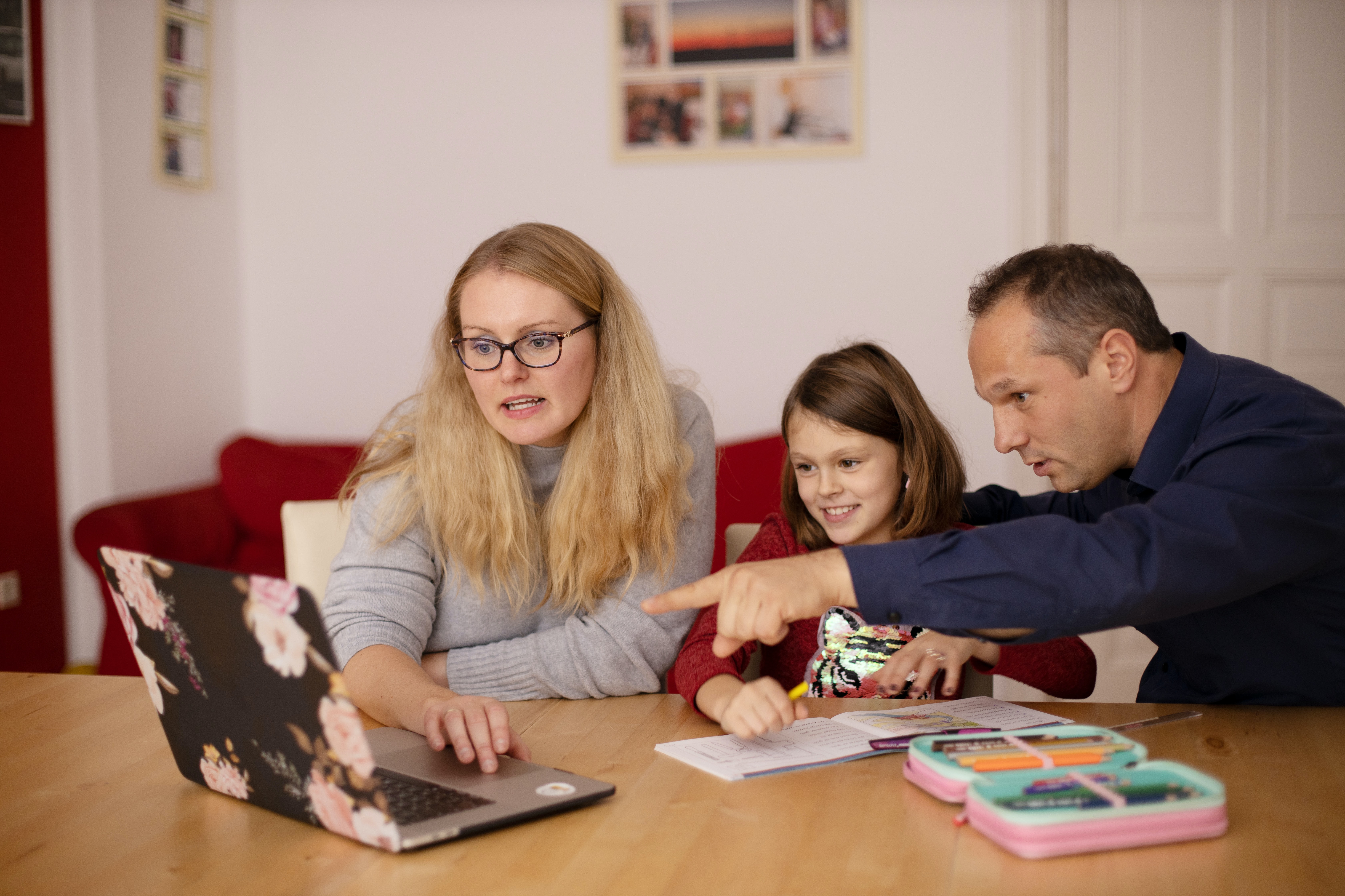 Two adults helping a child with homework at a table