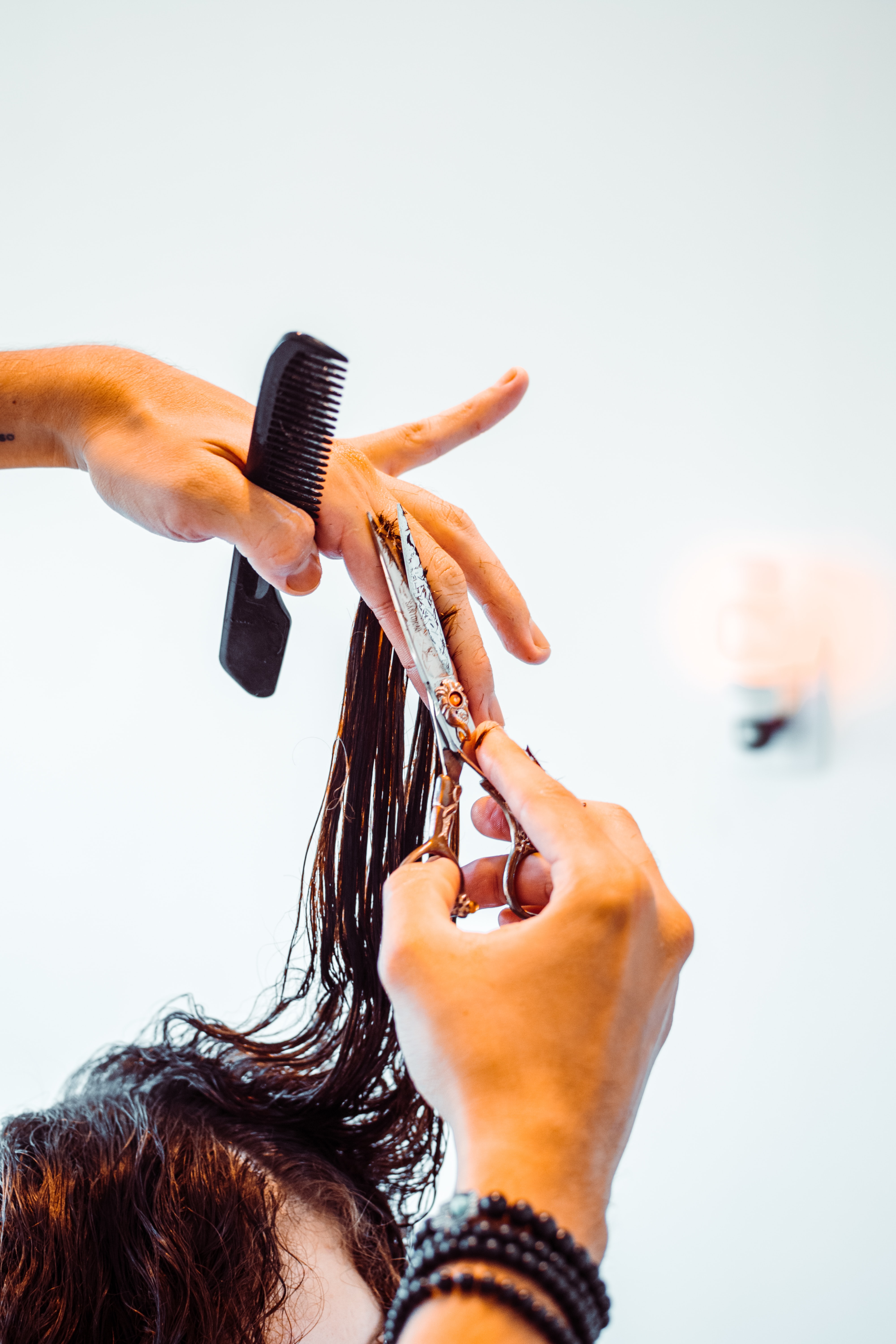 A beauty stylist carefully trimming a client's hair with shears