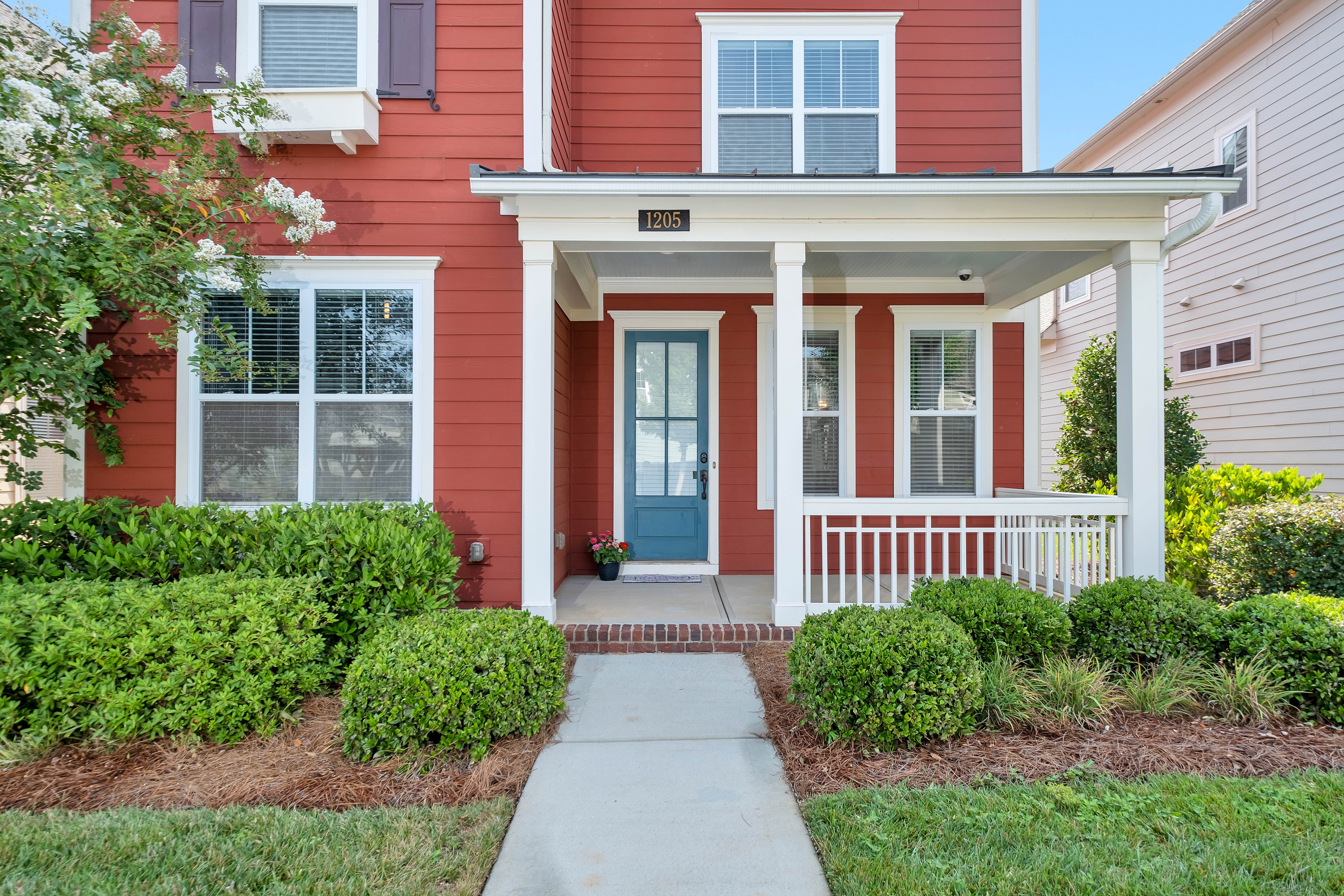 Two story house with small shrubs and bushes in front