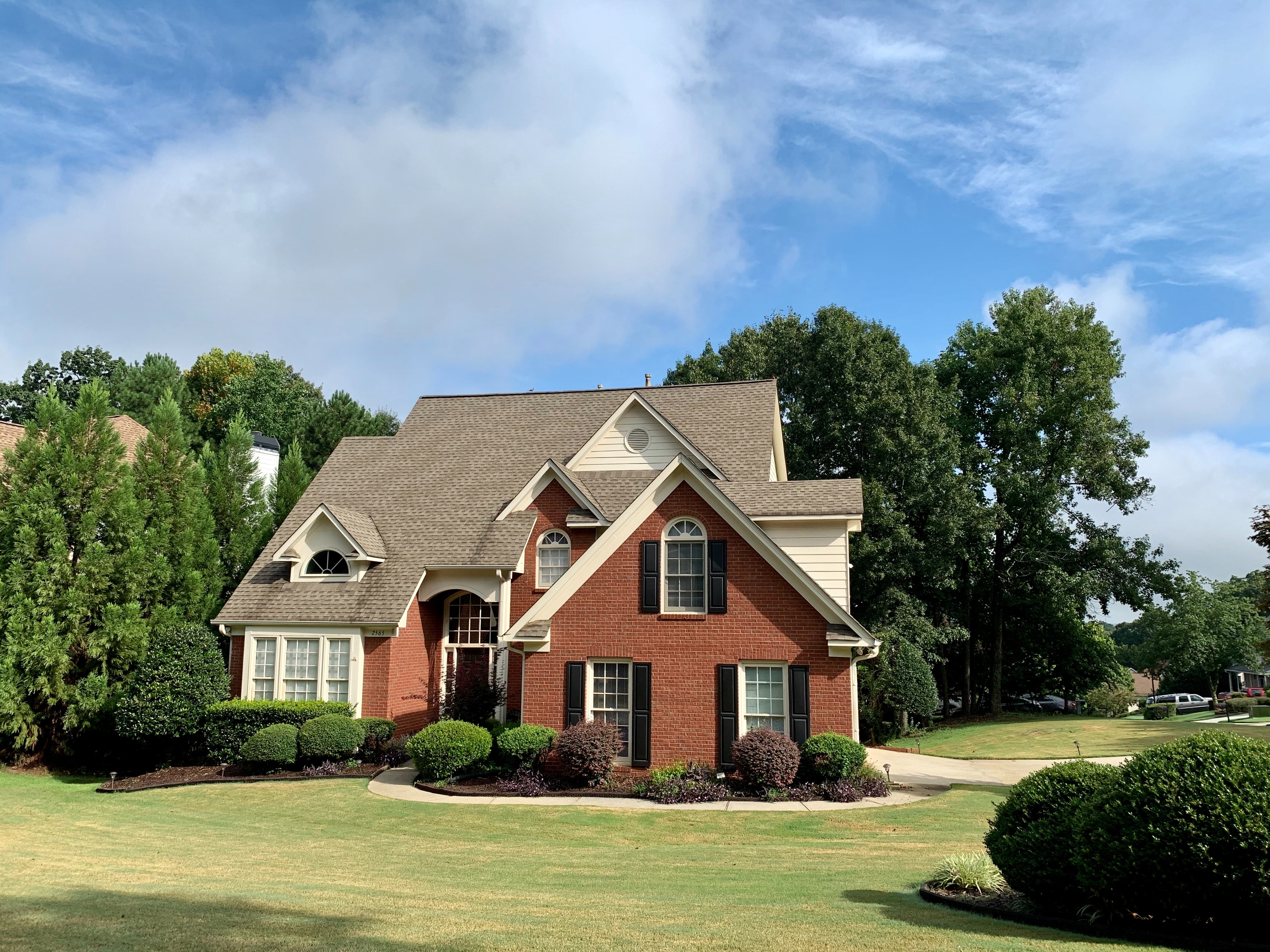 Red brick two story home on a large green grass property